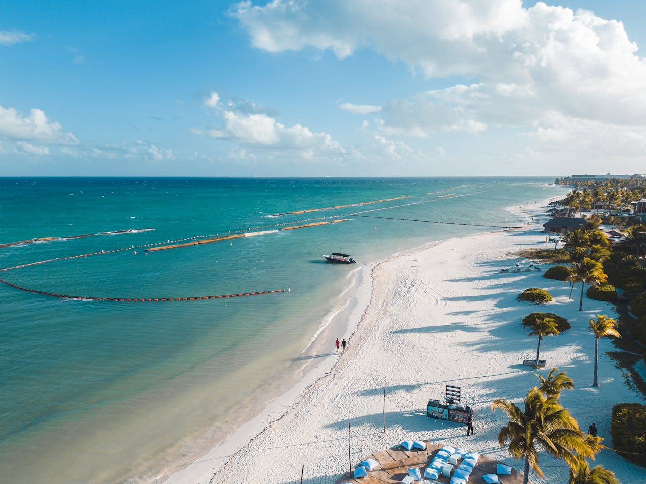 Services A beautiful aerial view of Playa del Carmens white sandy beach with clear blue waters and palm trees swaying in the tropical breeze.